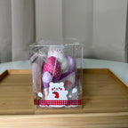 iBLOOM Blueberry Cake Marmo bear squishy side view in original display packaging with purple cake slice and large strawberry