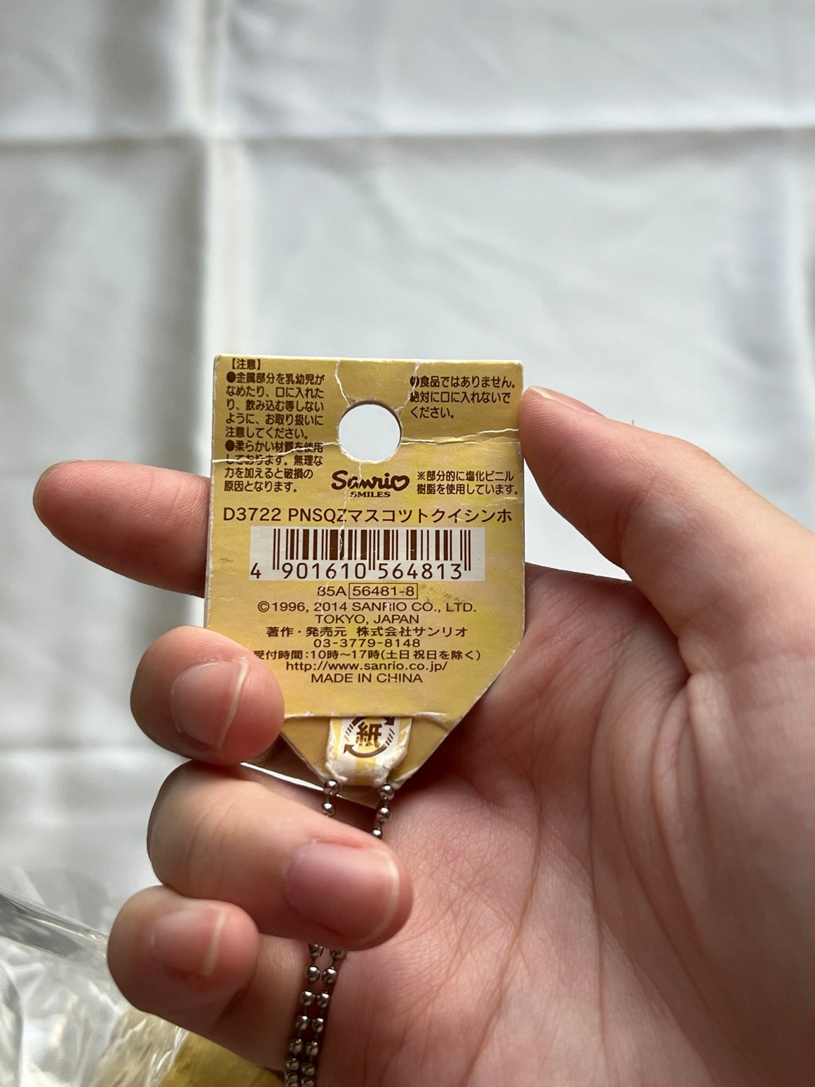 Back of original Sanrio Pompompurin squishy hang tag showing barcode 4901610564813 and aged paper creases