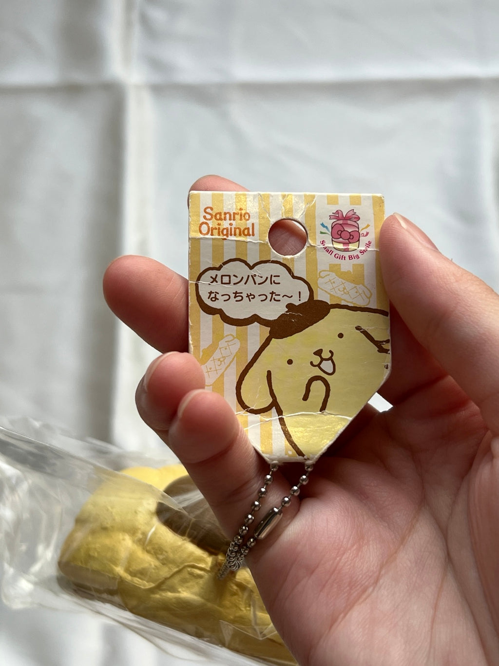 Original Sanrio Pompompurin melon bread squishy front hang tag with visible creases and ball chain