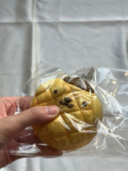 Front view of vintage Sanrio Pompompurin melon bread squishy in original plastic packaging showing extensive cracks and age-related damage